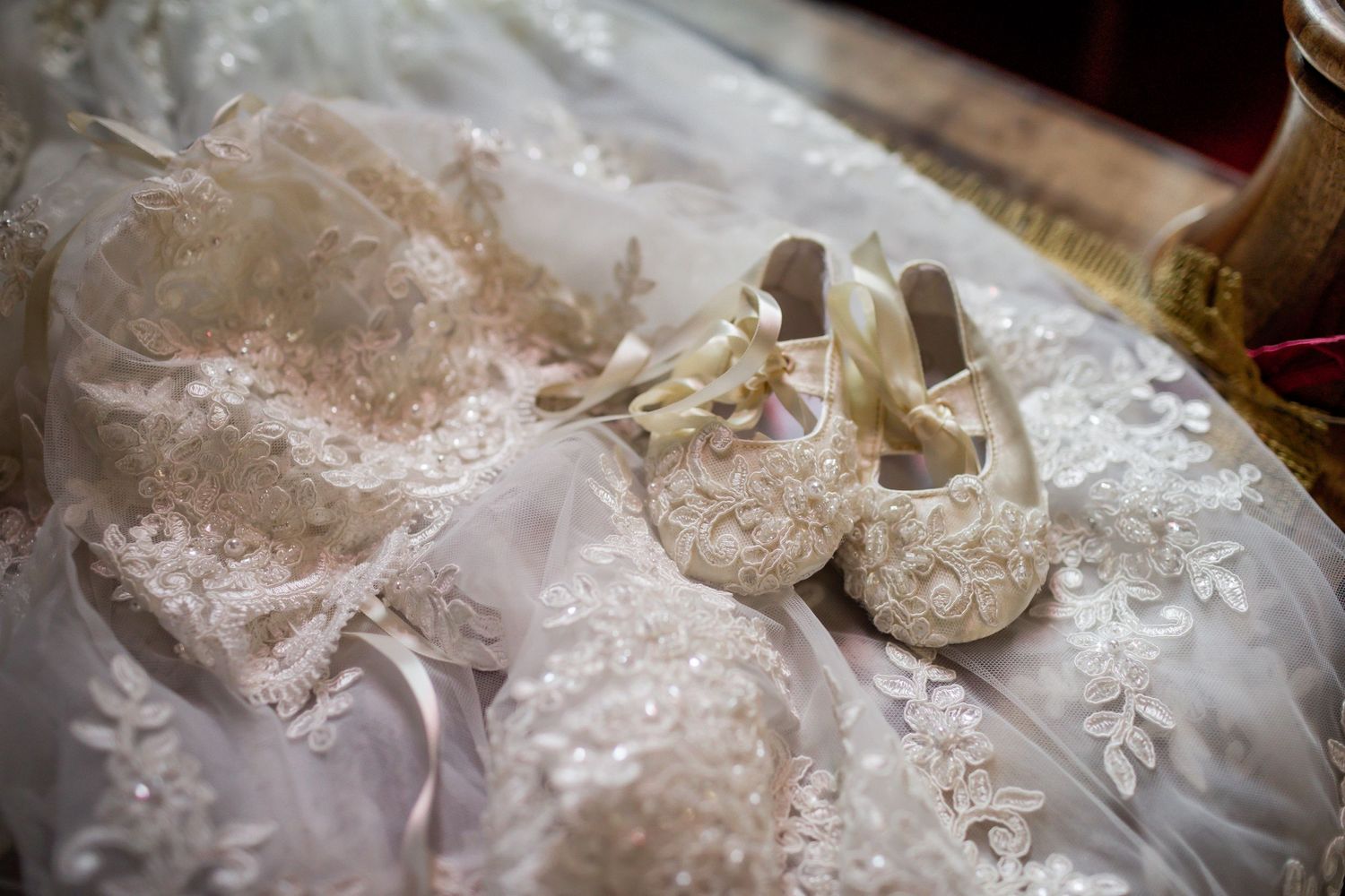 White lace christening gown and tiny embellished baby shoes on display.