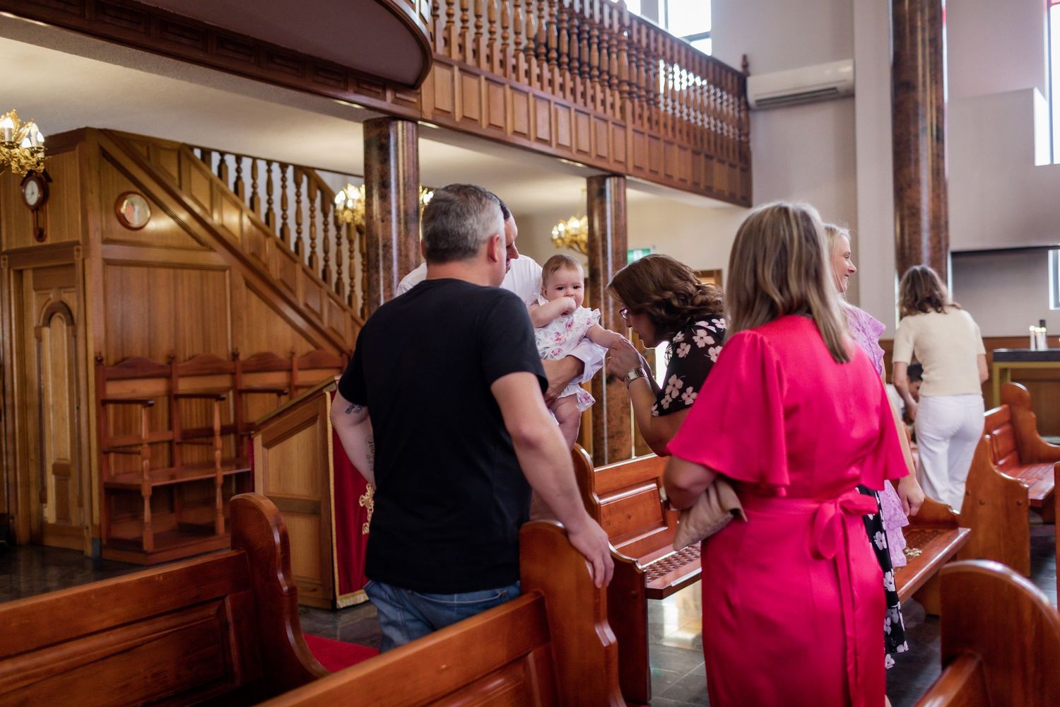 People gather near wooden pews and staircase inside church during religious ceremony.