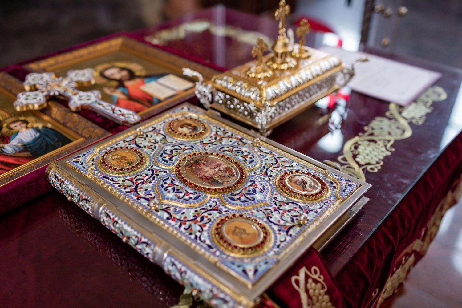 Ornate golden religious book with decorative details displayed on red cloth.