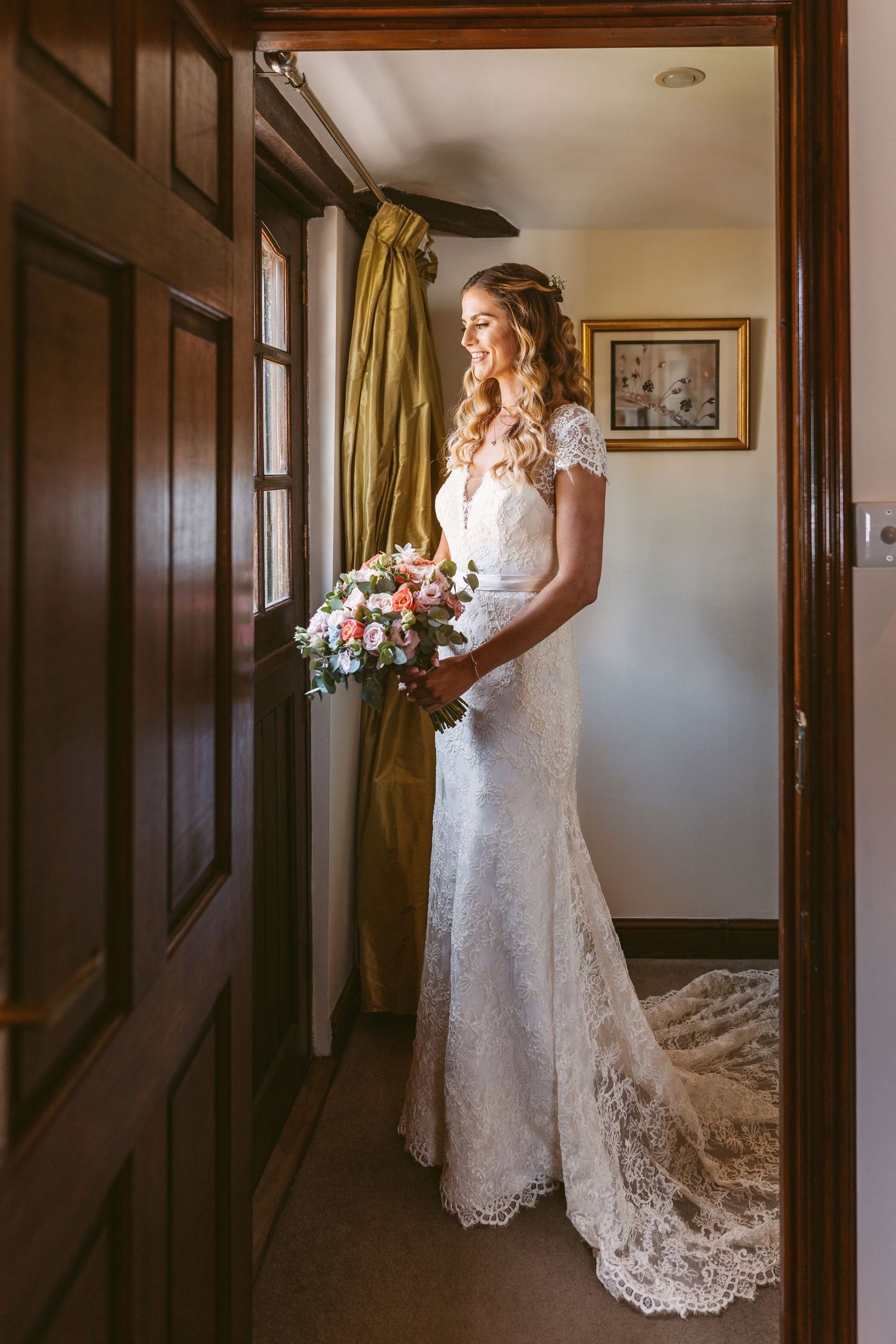 Beautiful lace wedding dress with long train photographed in a rustic hallway.