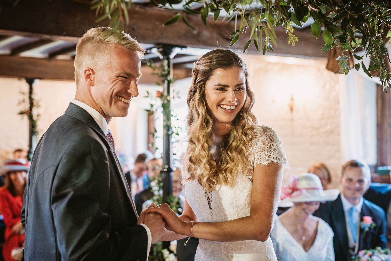 Joyful wedding ceremony moment under greenery-adorned pergola with natural lighting.