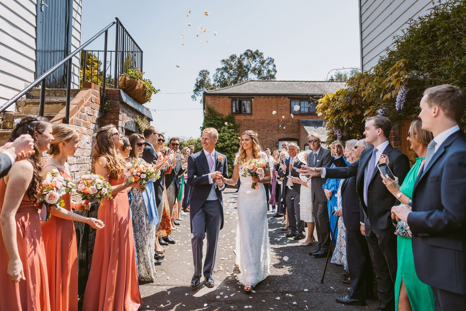 Wedding party and guests create confetti celebration line outdoors.