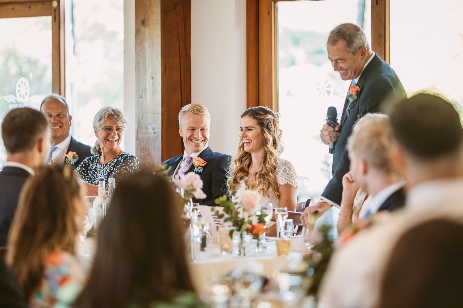 Wedding reception dinner scene with guests seated at decorated tables during speeches.