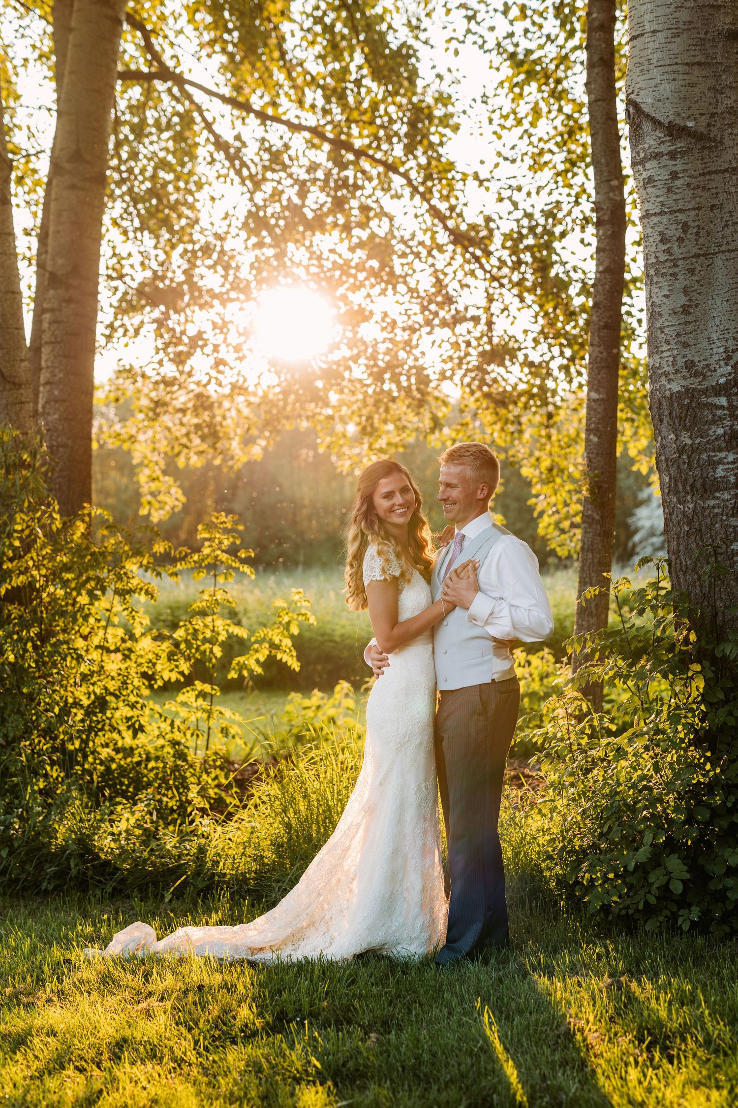 A romantic wedding portrait in a sun-drenched birch grove during golden hour.