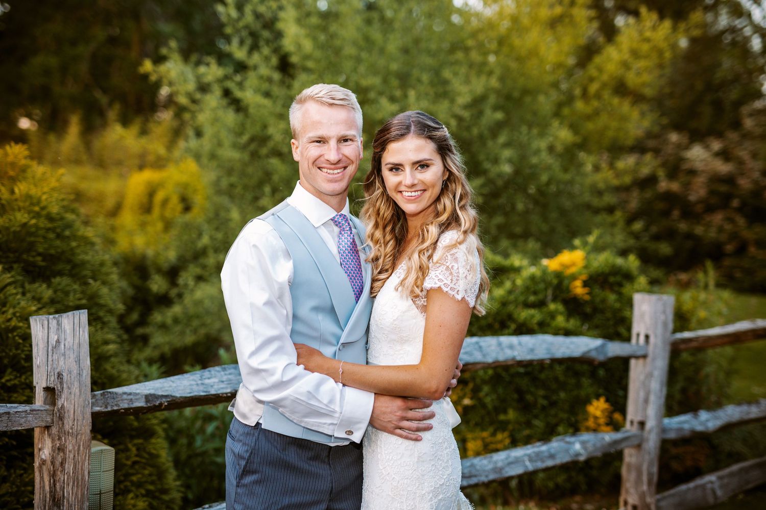 Couple posing for a romantic portrait by a rustic wooden fence during autumn.