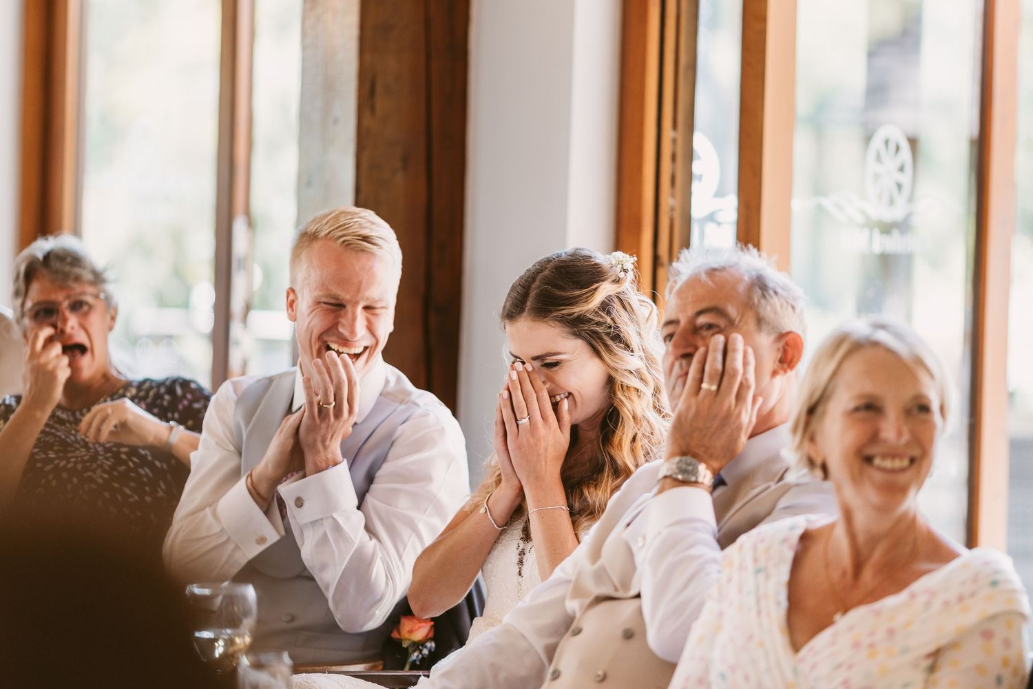 Emotional wedding guests react with joy during reception speeches.