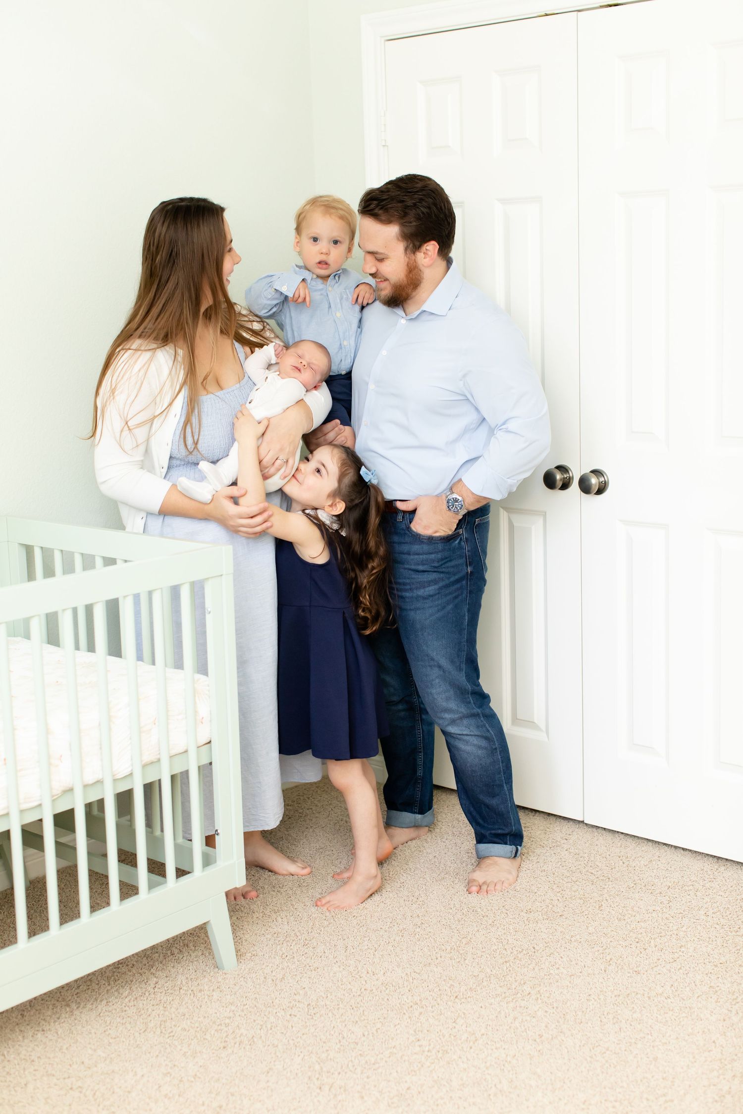 Family standing together in nursery room with white crib.