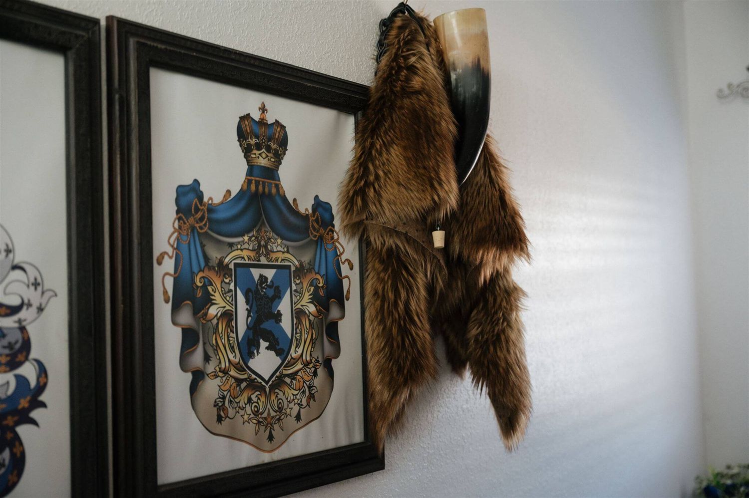 A blue heraldic crest hangs on the wall next to fur pelts in a medieval-themed room.