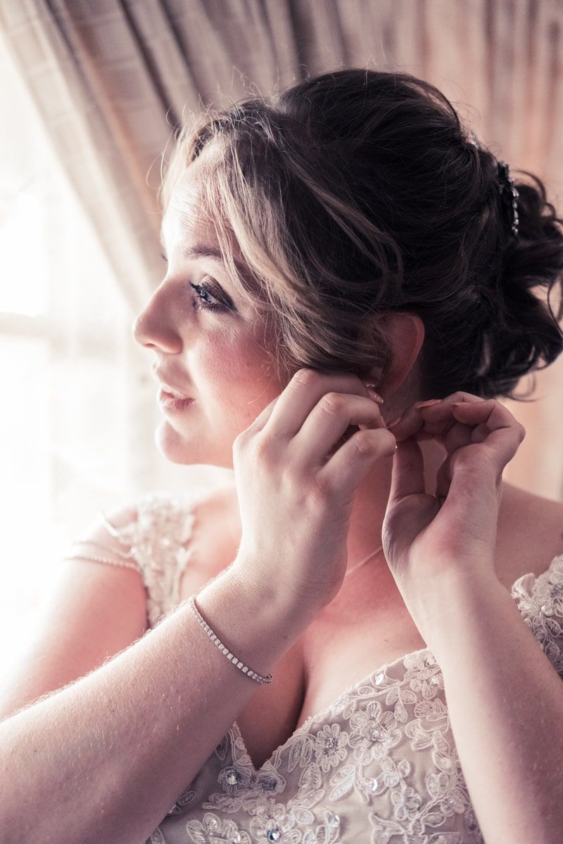 Bride during bridal prep putting in earring