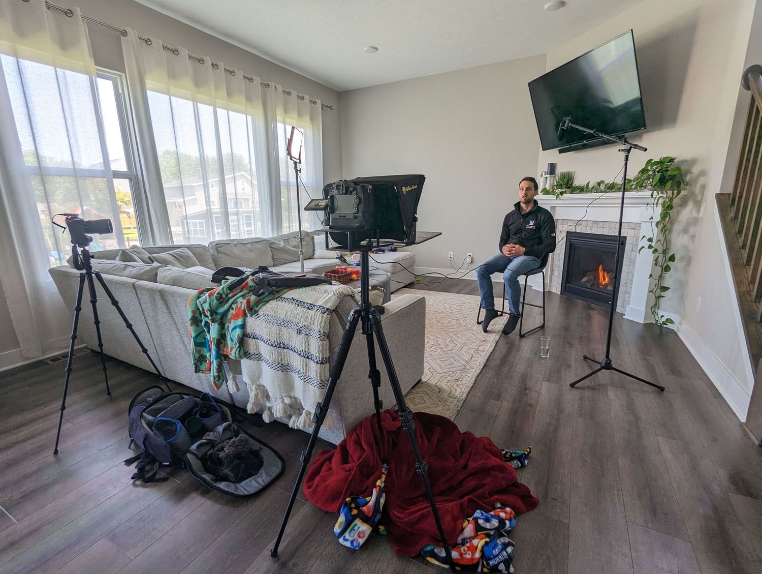 Modern apartment interior with photography equipment setup and natural lighting from large windows.