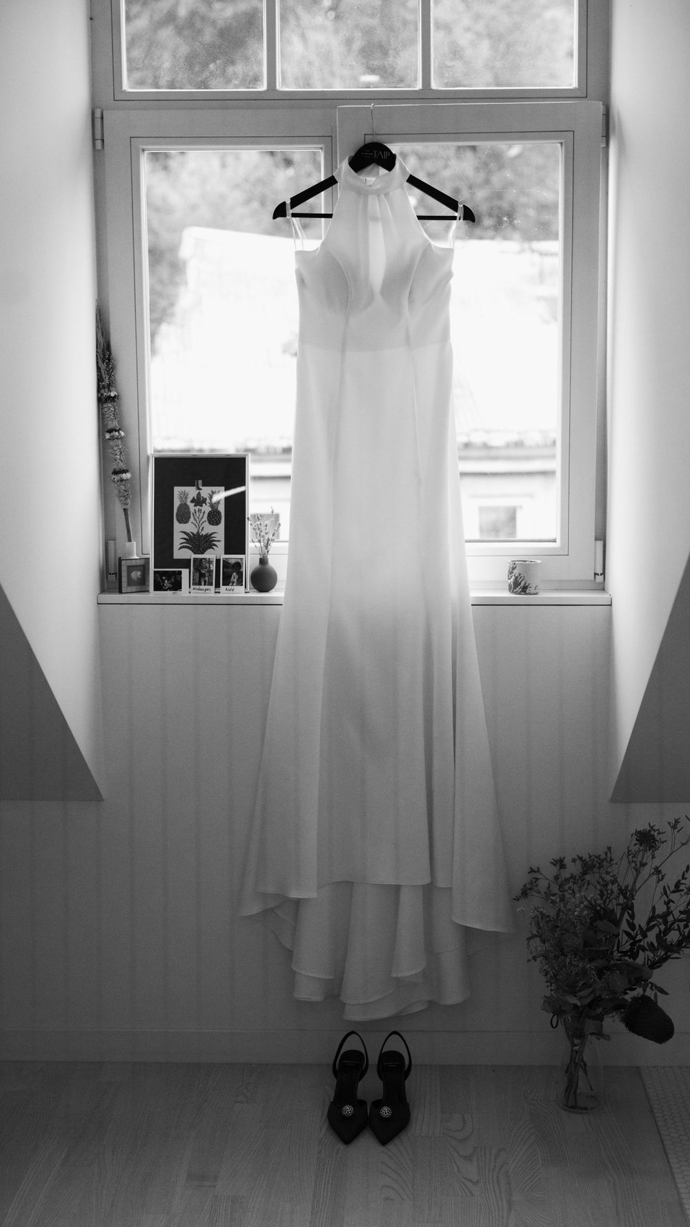 A bride's dress is hanging against the window.