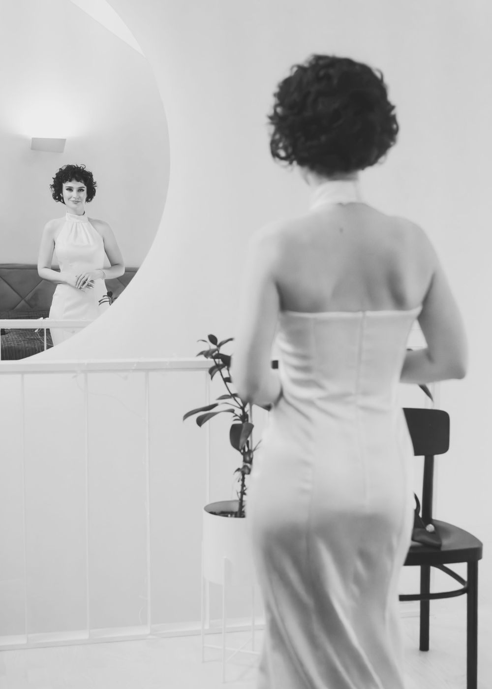 A woman in a bride's dress looking at the mirror.