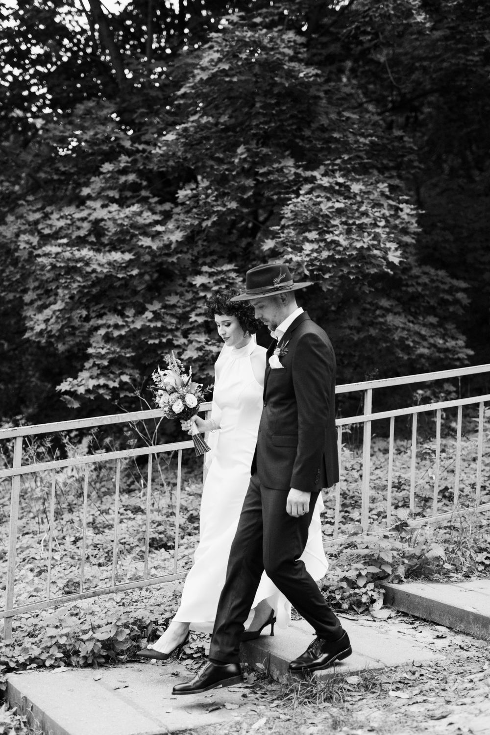 A bride and a groom walk down the stairs.