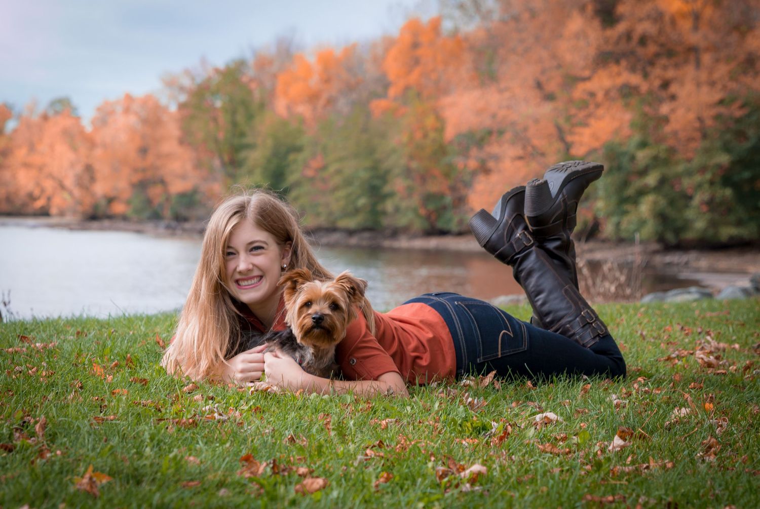 People and their dog enjoying a fall day laying in colorful autumn leaves.