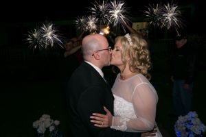 Couple sharing a kiss with fireworks display in the night sky.
