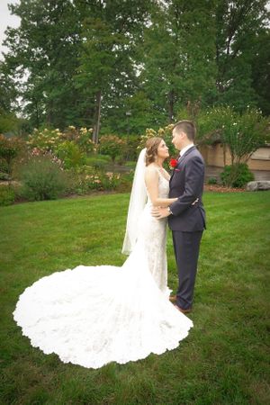 A stunning bridal portrait showcasing a dramatic cathedral-length lace train in a garden setting.