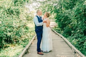 A romantic moment captured on a wooden boardwalk surrounded by lush greenery.