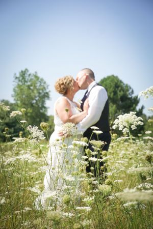 A romantic wedding portrait in a field of Queen Anne's lace flowers on a sunny summer day.
