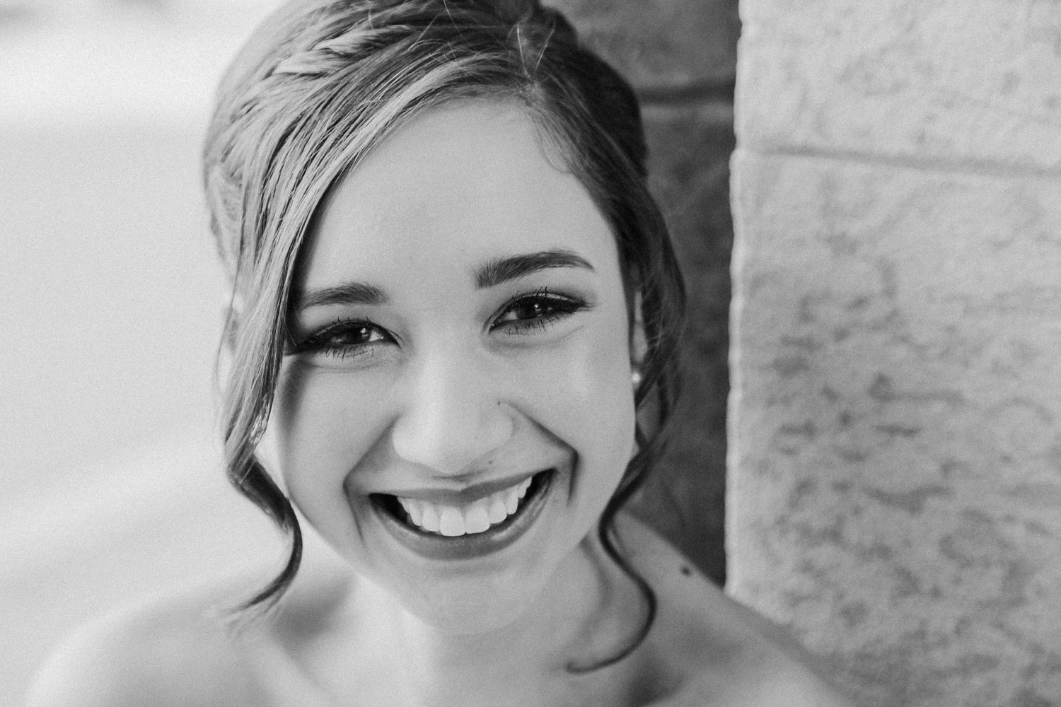 Beautiful bride with updo and radiant smile posing in a stunning black and white portrait.
