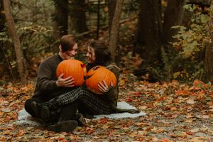Romantic autumn couple photoshoot with pumpkins on fallen leaves.