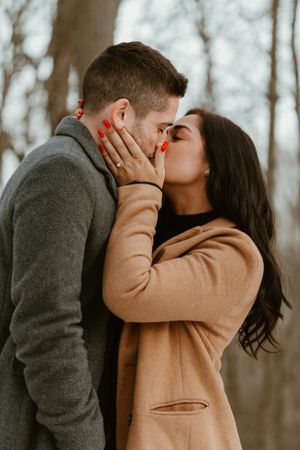 Intimate moment captured between couple in winter coats during outdoor photoshoot.