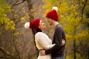 Winter engagement photos with couple in red beanies against yellow fall foliage.