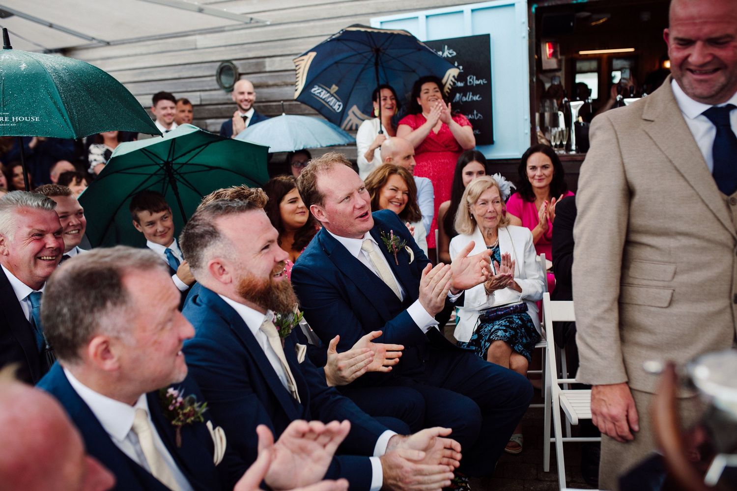 Wedding guests applauding during outdoor ceremony celebration.
