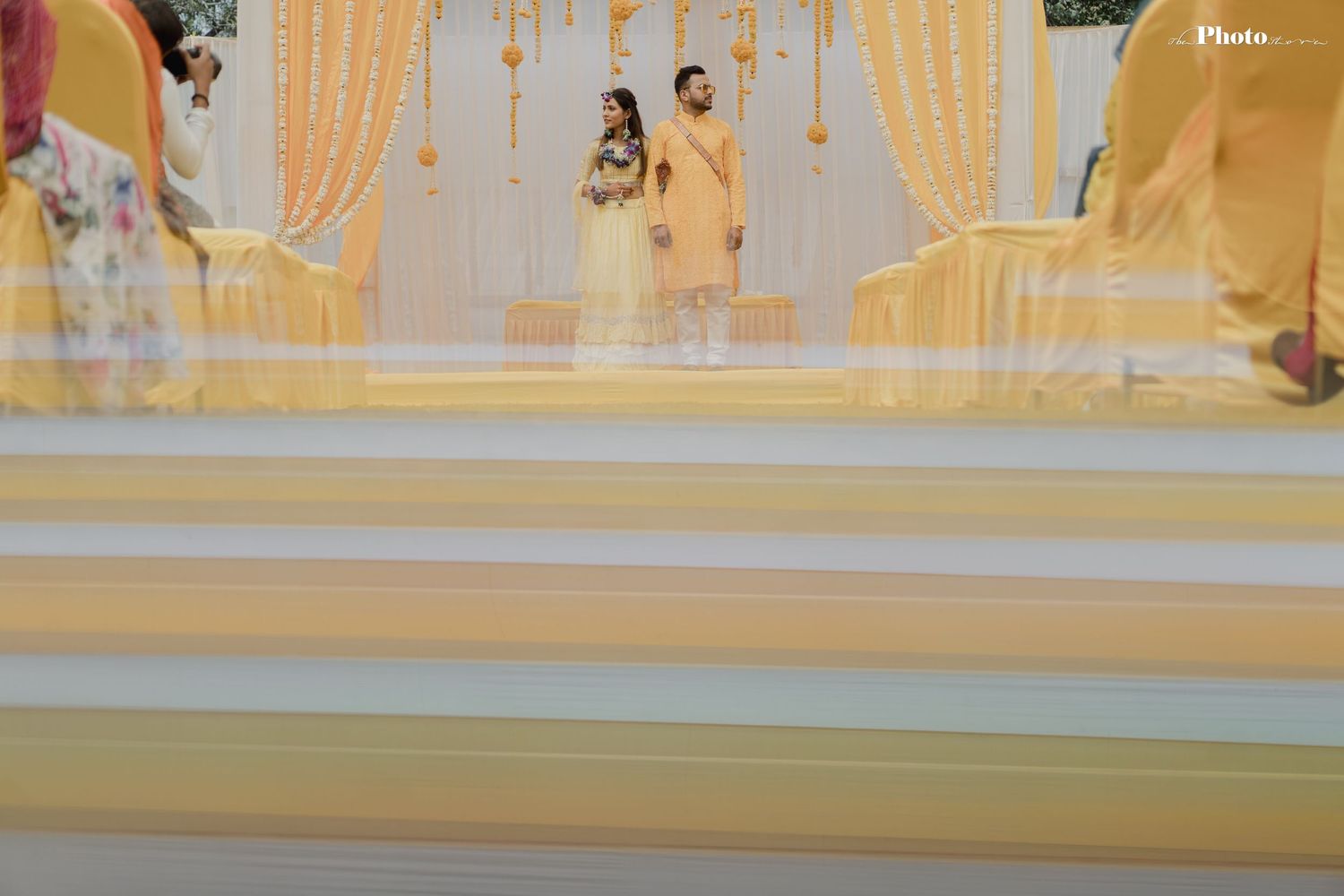 Elegant indoor venue decorated with yellow drapes and lighting for wedding celebration.