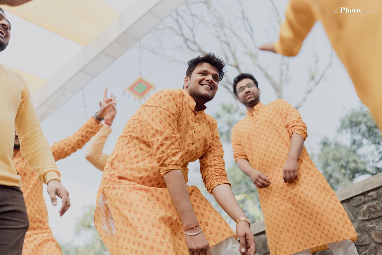 Group wearing matching yellow outfits celebrates during traditional ceremony.