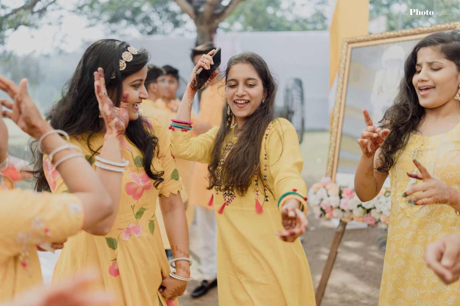 Bridesmaids in yellow dresses celebrate outdoors during wedding festivities.