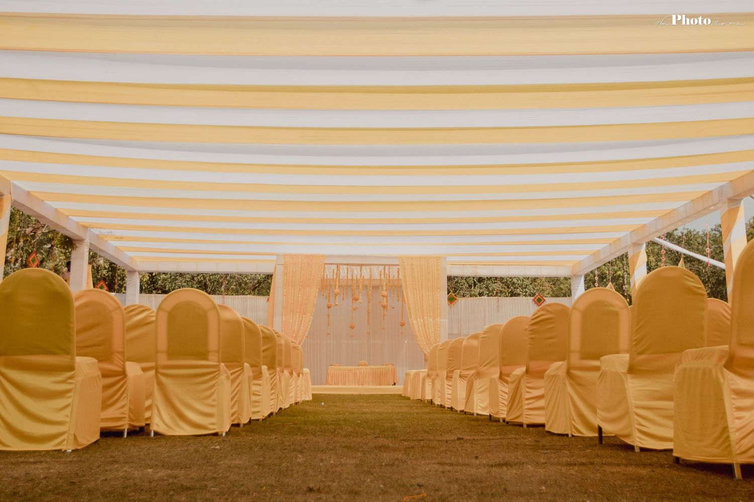 Elegant outdoor wedding venue setup with white draped canopy and rows of seating.