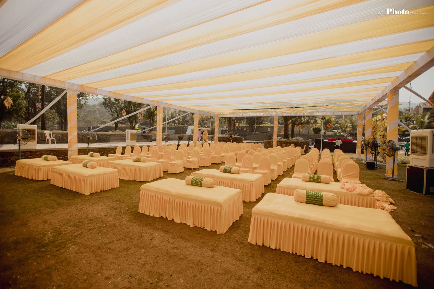 Reception area with long tables covered in cream linens under an outdoor tent structure.