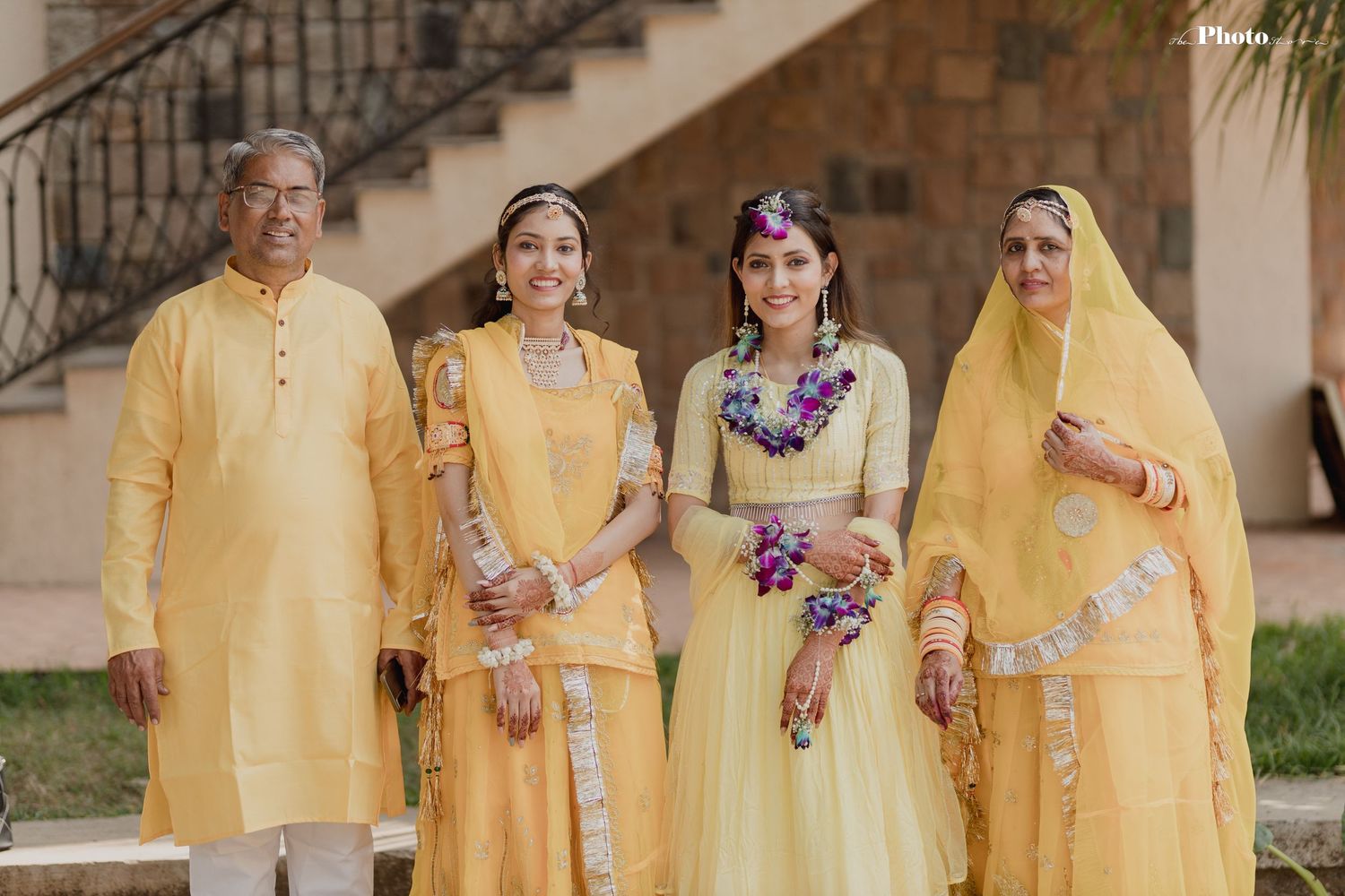Group wearing coordinated yellow traditional Indian attire poses on stone staircase.