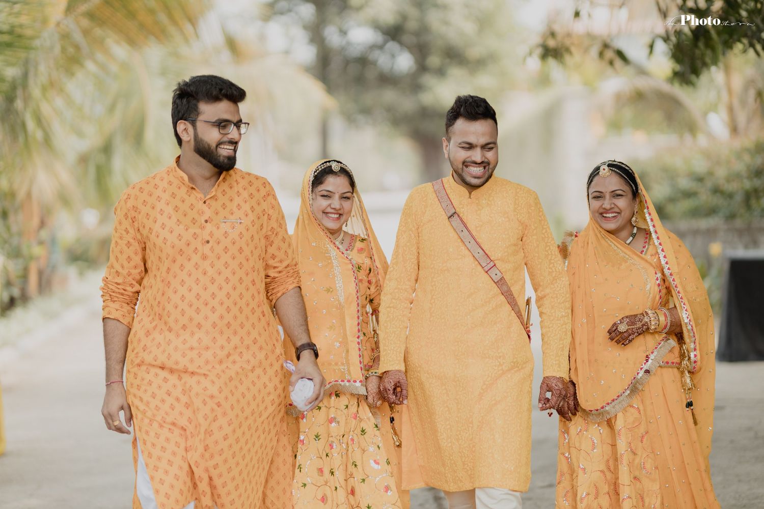 Family group wearing coordinated yellow and orange traditional Indian clothing poses outdoors.