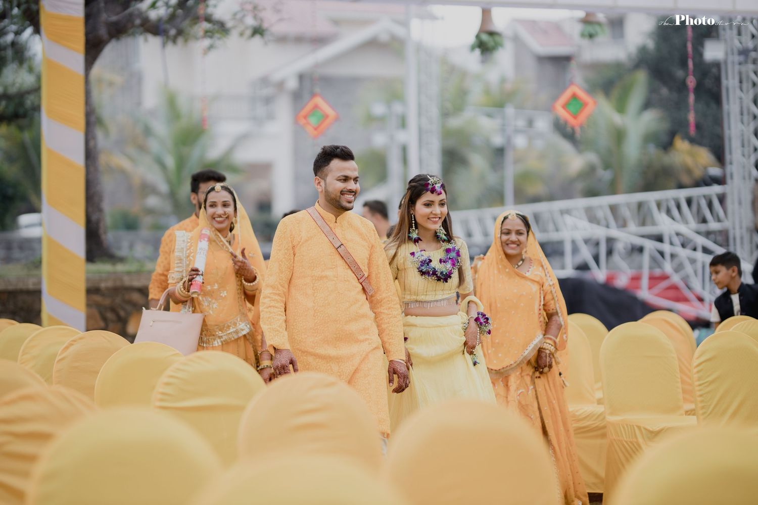 Wedding party in matching yellow and orange attire walks together during celebration.