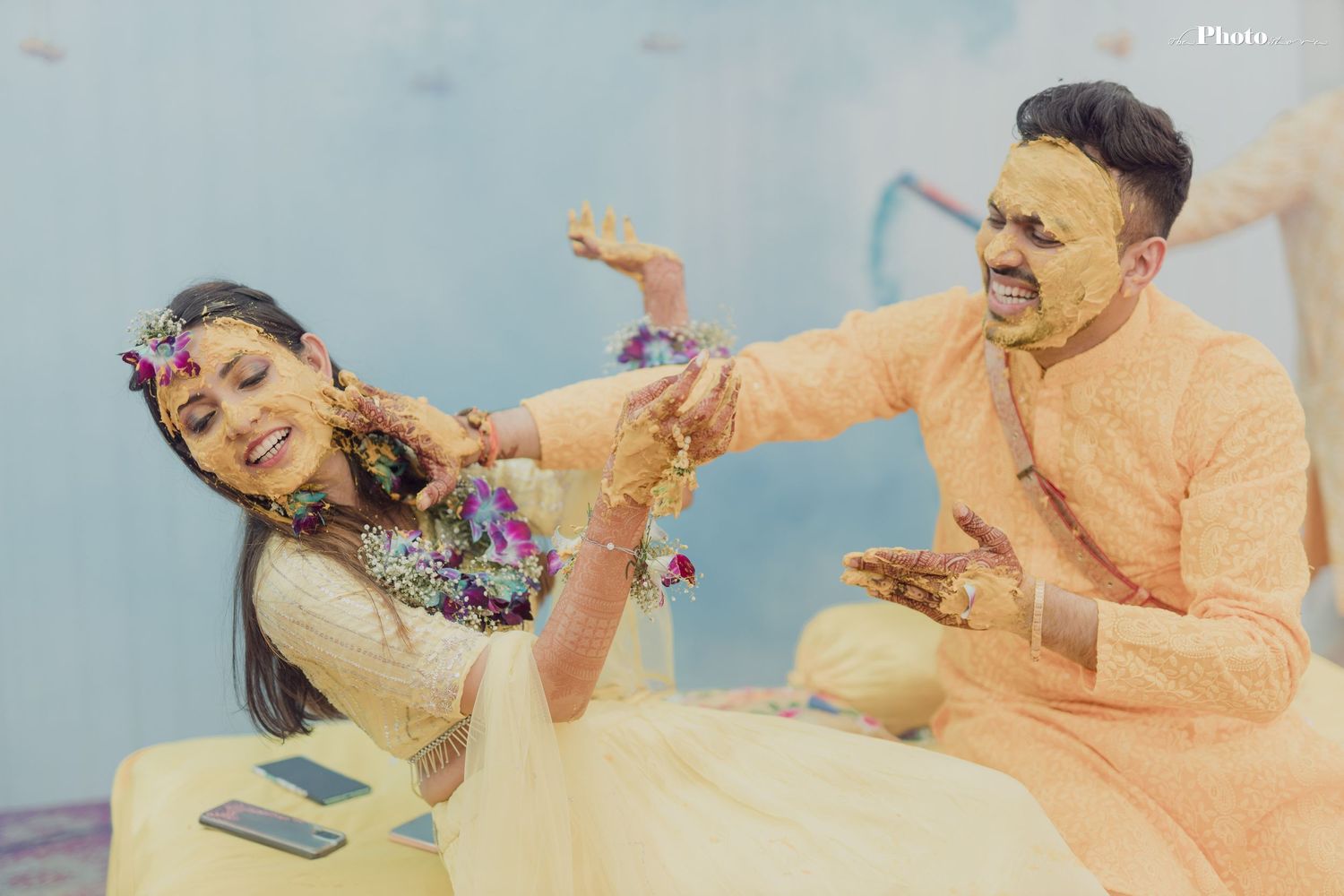 Couple playing and laughing during haldi ceremony with yellow turmeric powder.