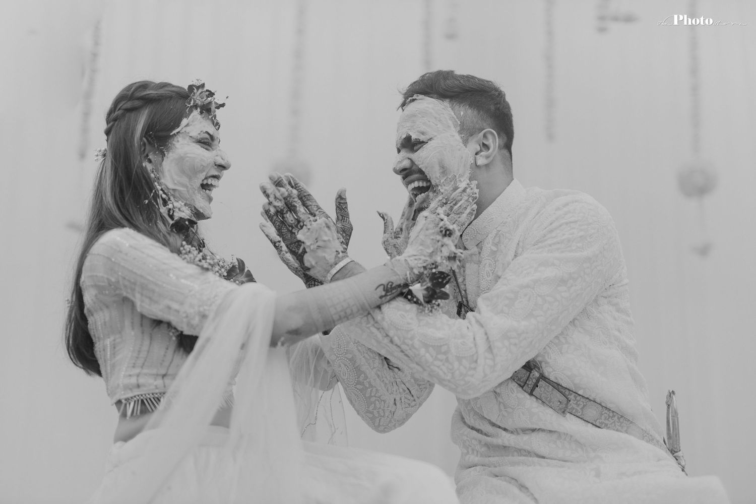 Black and white capture of playful moment during Indian wedding traditions.
