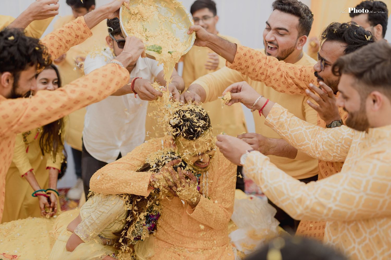 Friends throwing yellow turmeric powder during traditional haldi ceremony celebrations.