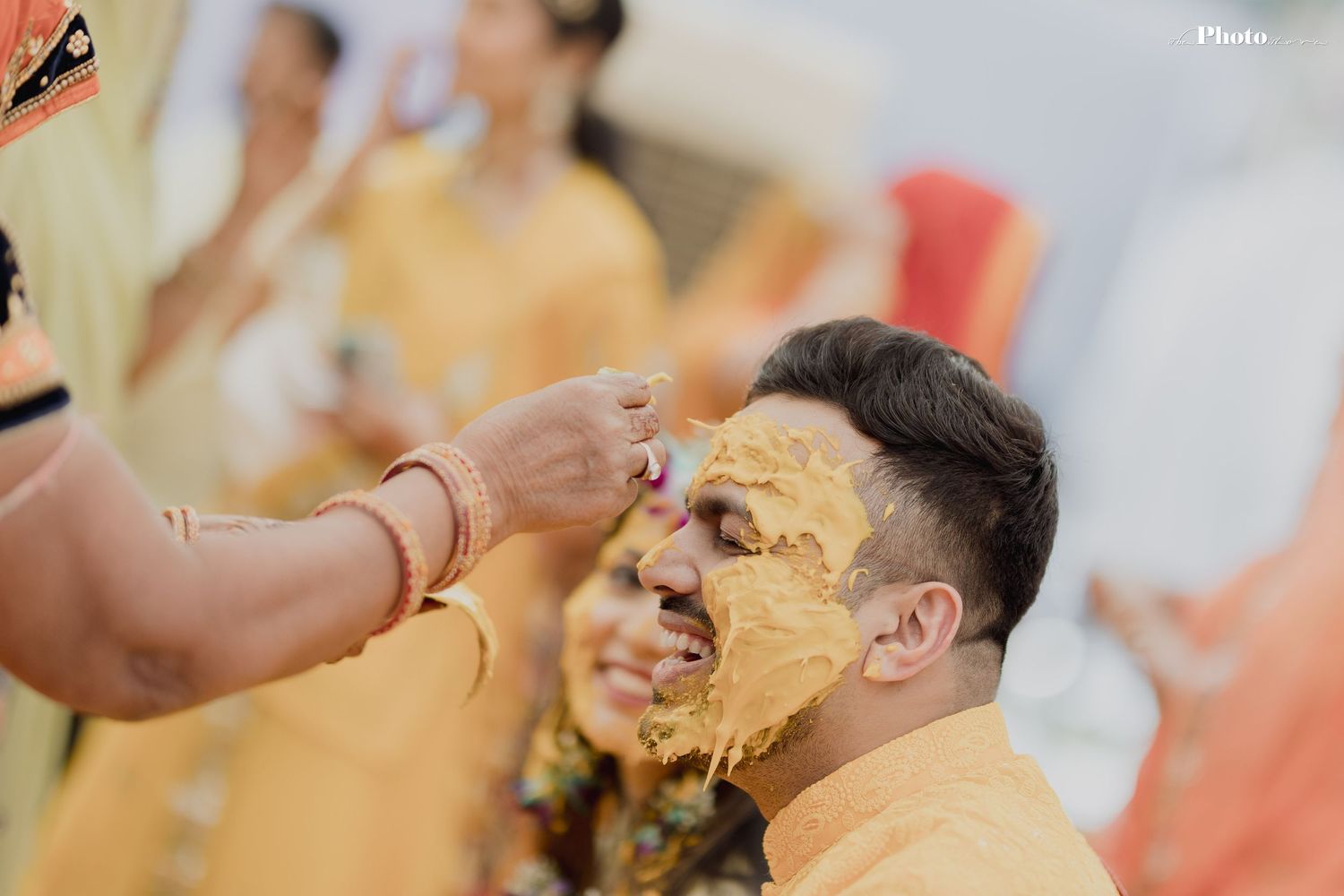 Celebratory moment at Indian wedding as guests participate in traditional Haldi powder ceremony.
