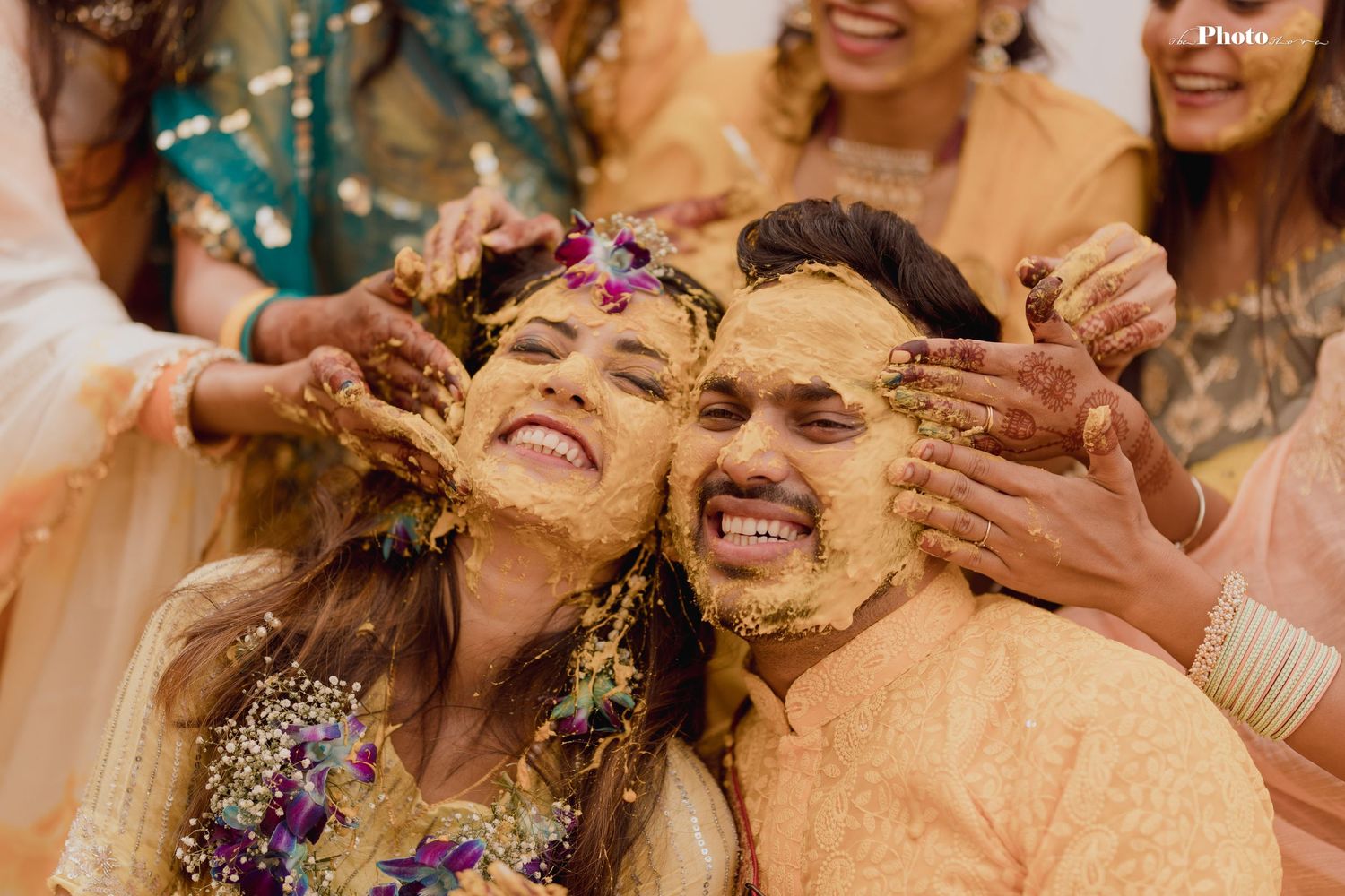 Wedding celebration features guests in teal and peach outfits enjoying traditional Haldi ceremony.