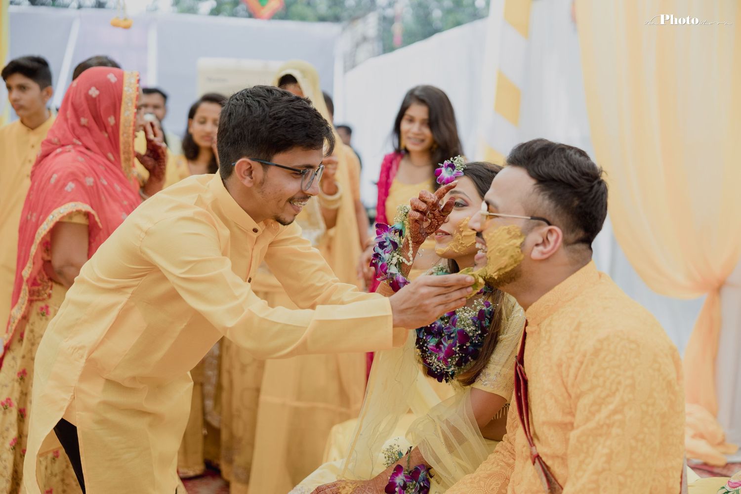 Wedding party members in yellow traditional clothing gather for Haldi ceremony celebrations.