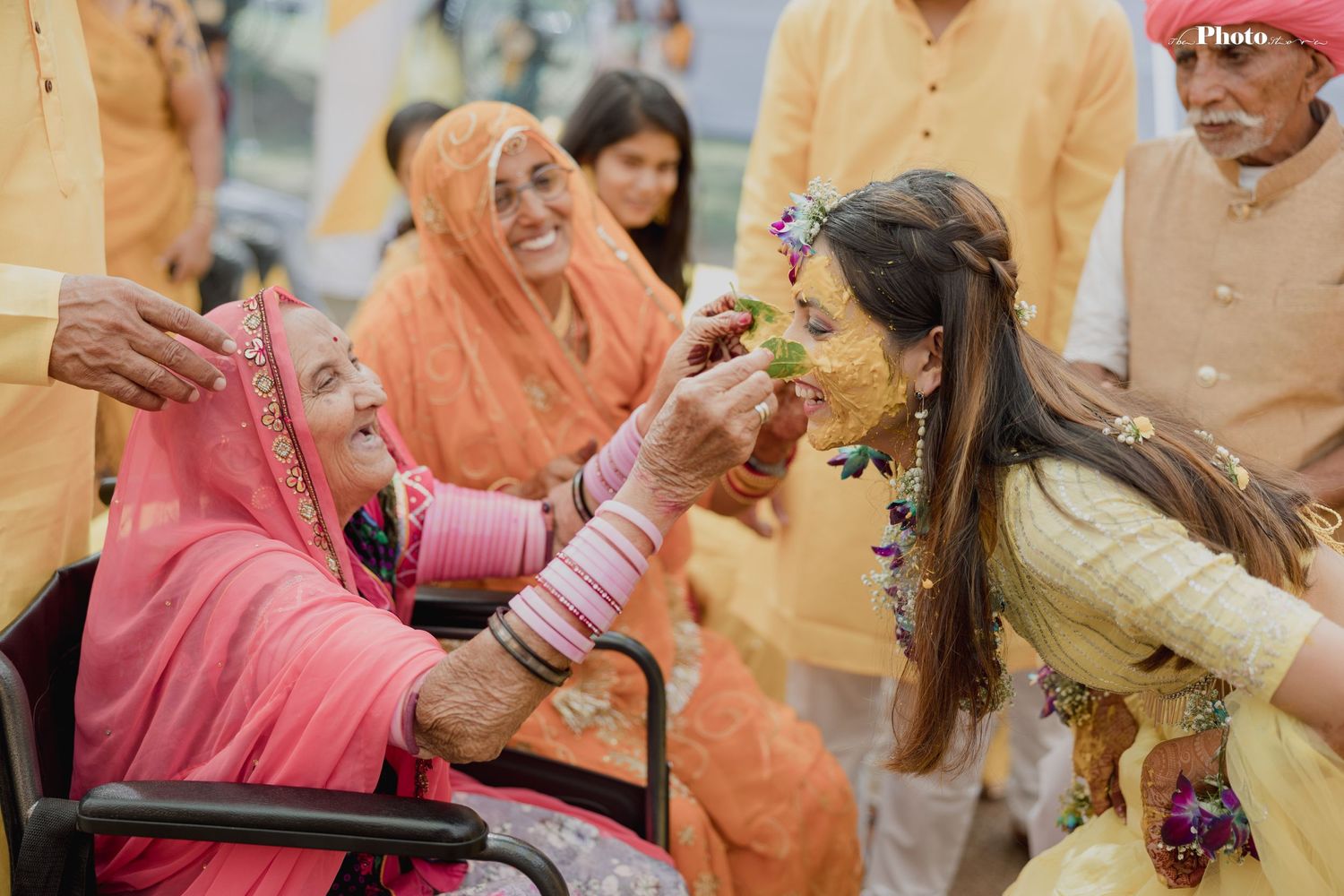 Festive group wearing yellow attire celebrates during a traditional Indian pre-wedding ceremony.