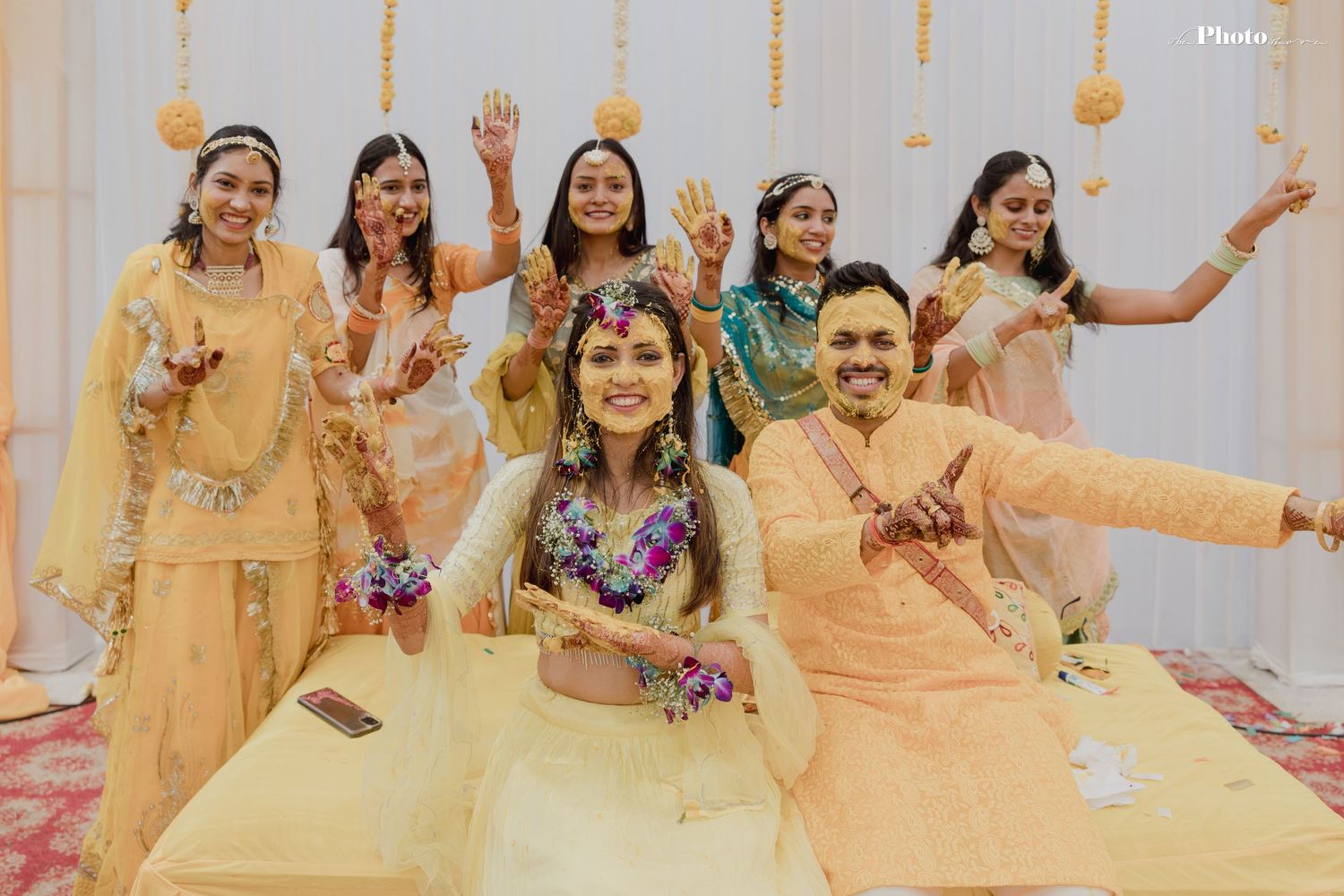 Bridesmaids in matching yellow outfits pose together during wedding celebrations.