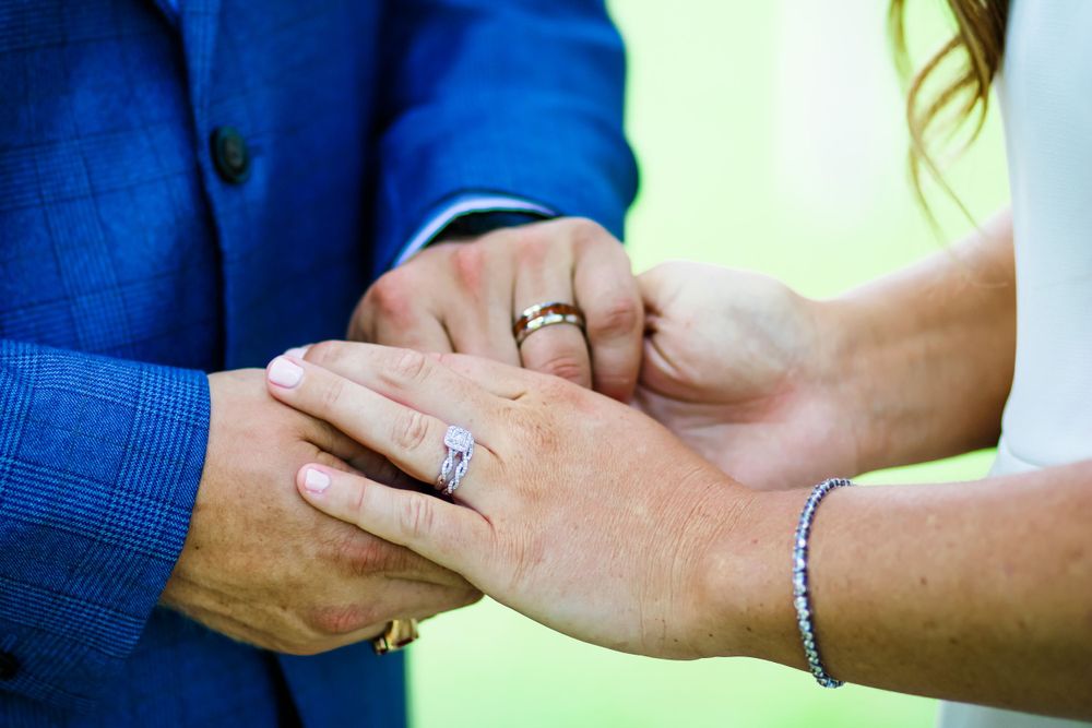Close-up of hands showing wedding rings during ceremony moment.