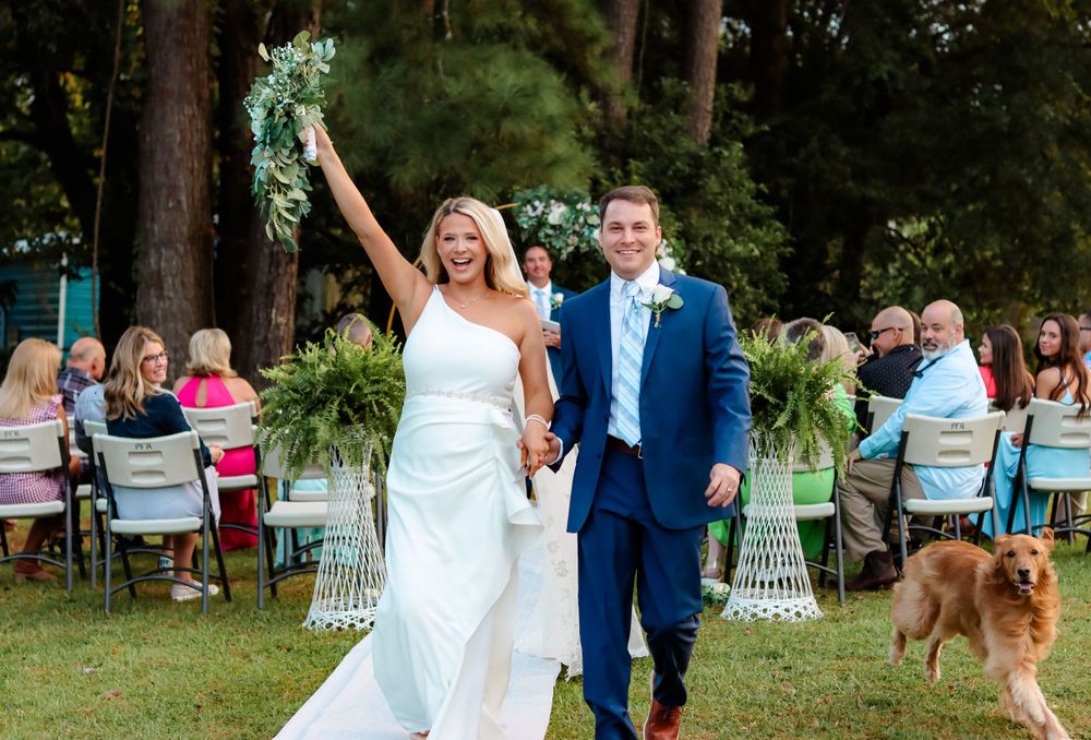 A celebratory wedding exit with guests and a dog watching in an outdoor garden setting.