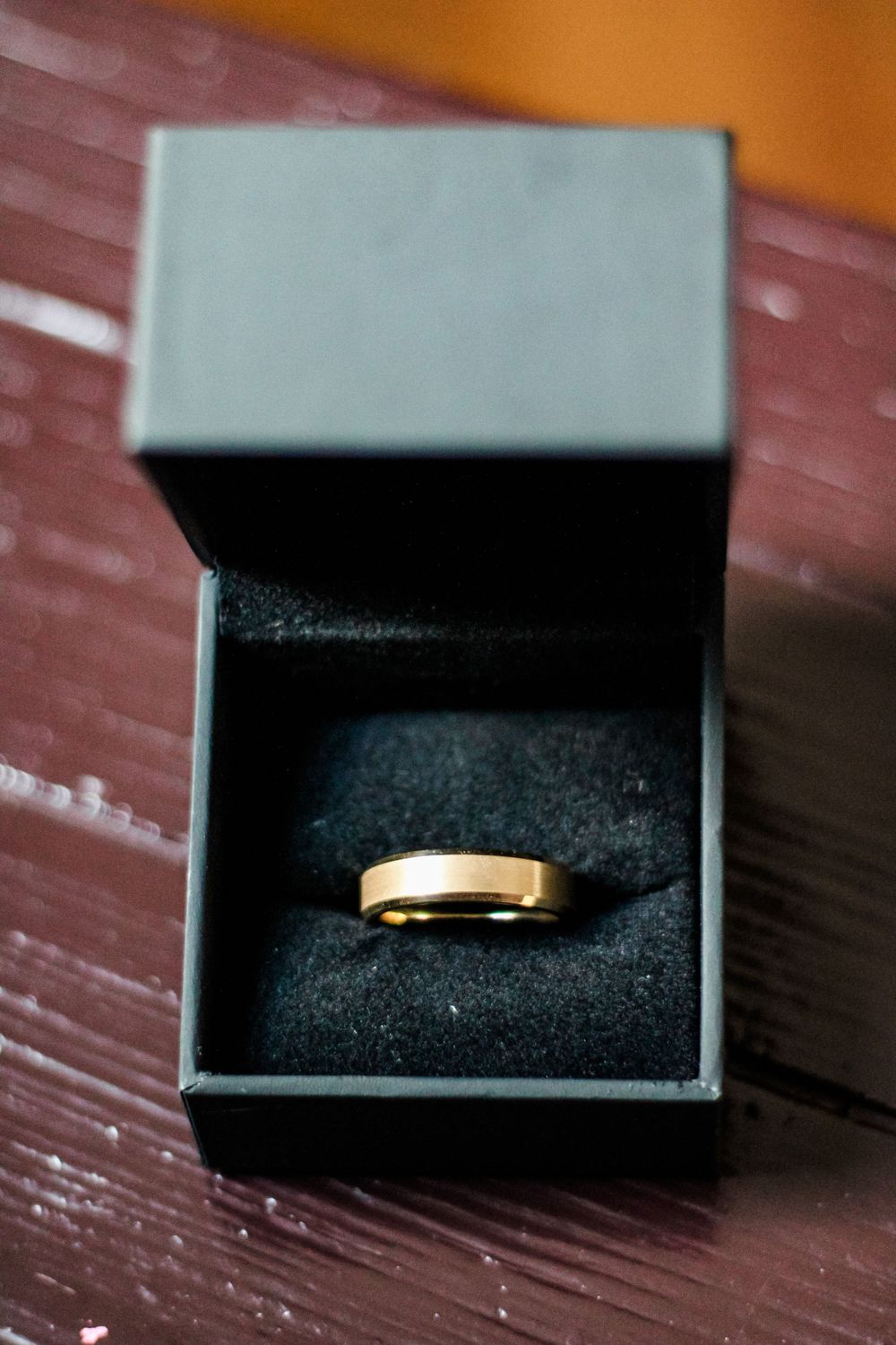 Gold wedding band displayed in an open black jewelry box.