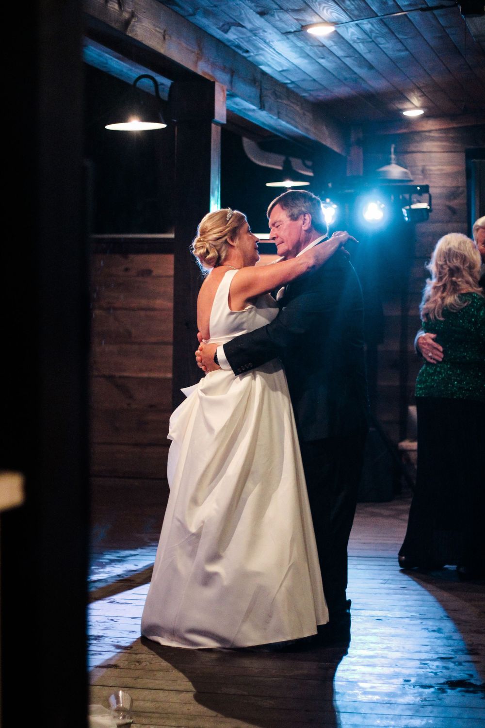 A romantic first dance between newlyweds in a rustic wooden venue with mood lighting.