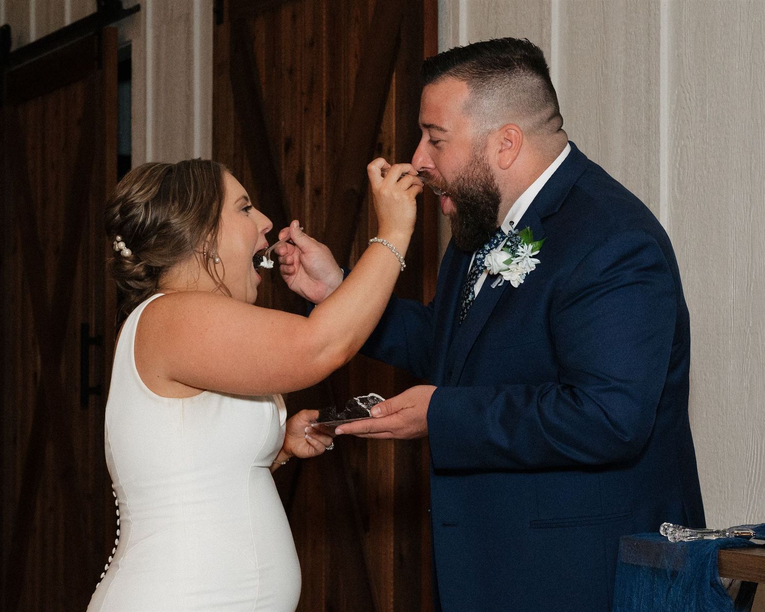 A playful cake-feeding moment between the couple at their wedding reception.