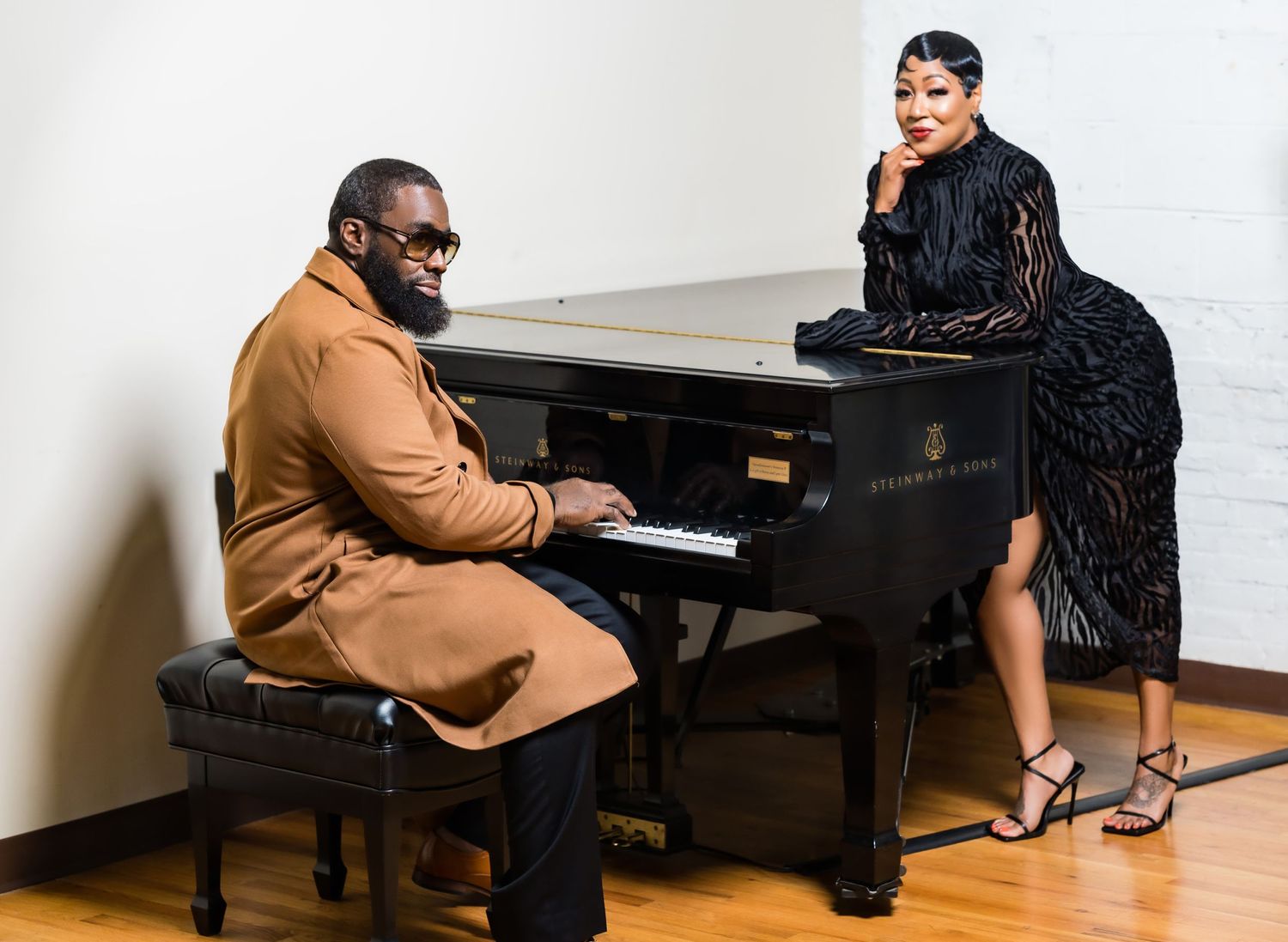 Couple performing duet at grand piano in formal attire.