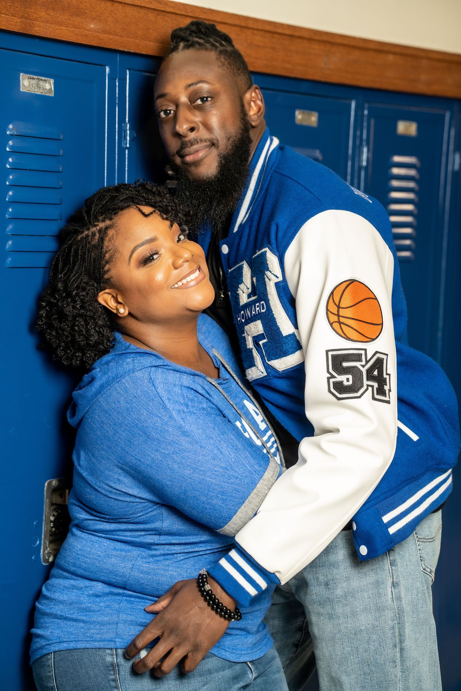 Athletic couple in blue team apparel poses by school lockers.